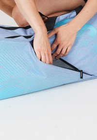 Sininen duffel-laukku, jossa on texturoitu pinta, n�ähtävissä kontrastina turkoosi kuvio ja mustat kahvat. Avoin vetoketju paljastaa tilavan sisäosan.