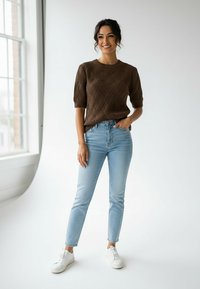 Brązowy, teksturowany, dziergany sweter z krótkimi rękawami, zestawiony z jasnoniebieskimi, wysokim stanem dżinsami i białymi trampkami. Prosty, codzienny strój.