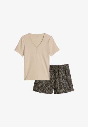 Beiges Henley-Shirt mit kurzen Ärmeln, kombiniert mit schwarzen Shorts, die ein kleines weißes Blumenmuster und einen elastischen Bund haben.