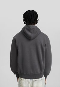 Mörkgrå hoodie med rundad halsringning, långa ärmar och känguruficka. Mjuk, texturerad väv med avslappnad passform.