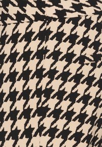 Motif textile pied-de-poule noir et beige avec des coutures visibles formant des lignes qui se croisent.