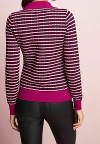 Gebreide trui met een gestreept ontwerp in roze, zwart en wit. Geribbelde manchetten en zoom in effen roze. Gevoelige oppervlakte met gevarieerde patronen.