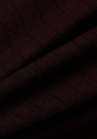 Dunkelburgunderfarbener Stoff mit gerippter Textur, der wellenförmige Linien aufweist. Weich und glatt, mit dezenten Mustern durchzogen.