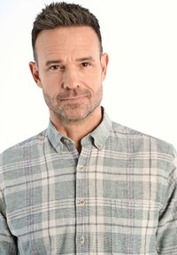 Camisa a cuadros en tonalidades de verde y blanco, con un bolsillo y un cuello, fabricada con un tejido suave.