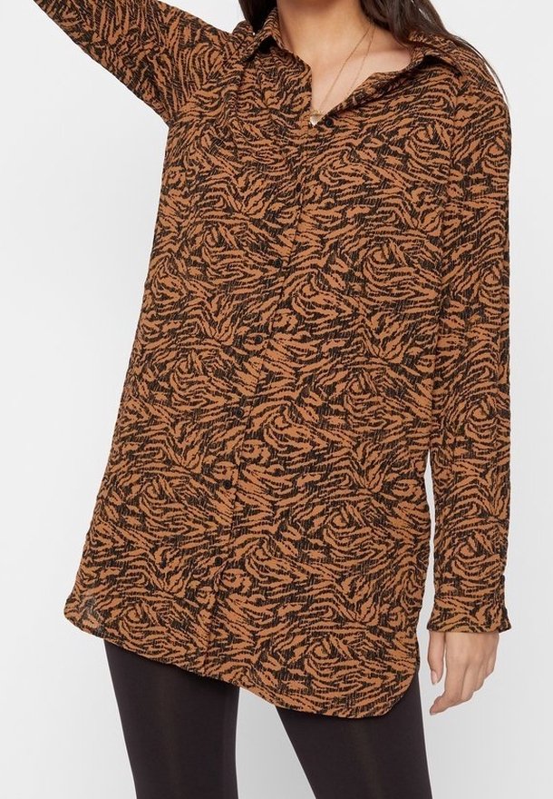 Camicia a maniche lunghe di colore marrone con un motivo astratto nero, dotata di colletto e chiusura con bottoni, realizzata in un tessuto testurizzato.