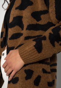 Brun och svart mönstrad cardigan med en mjuk textur och ribbade muddars, i en lös passform och med abstrakt leopardmönster.