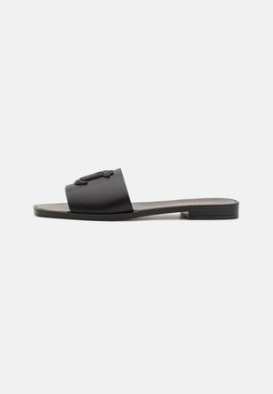 Black slide sandal featuring a smooth matte finish, a wide strap with logo detail, a flat sole, and a subtle heel. Designed for easy wear.