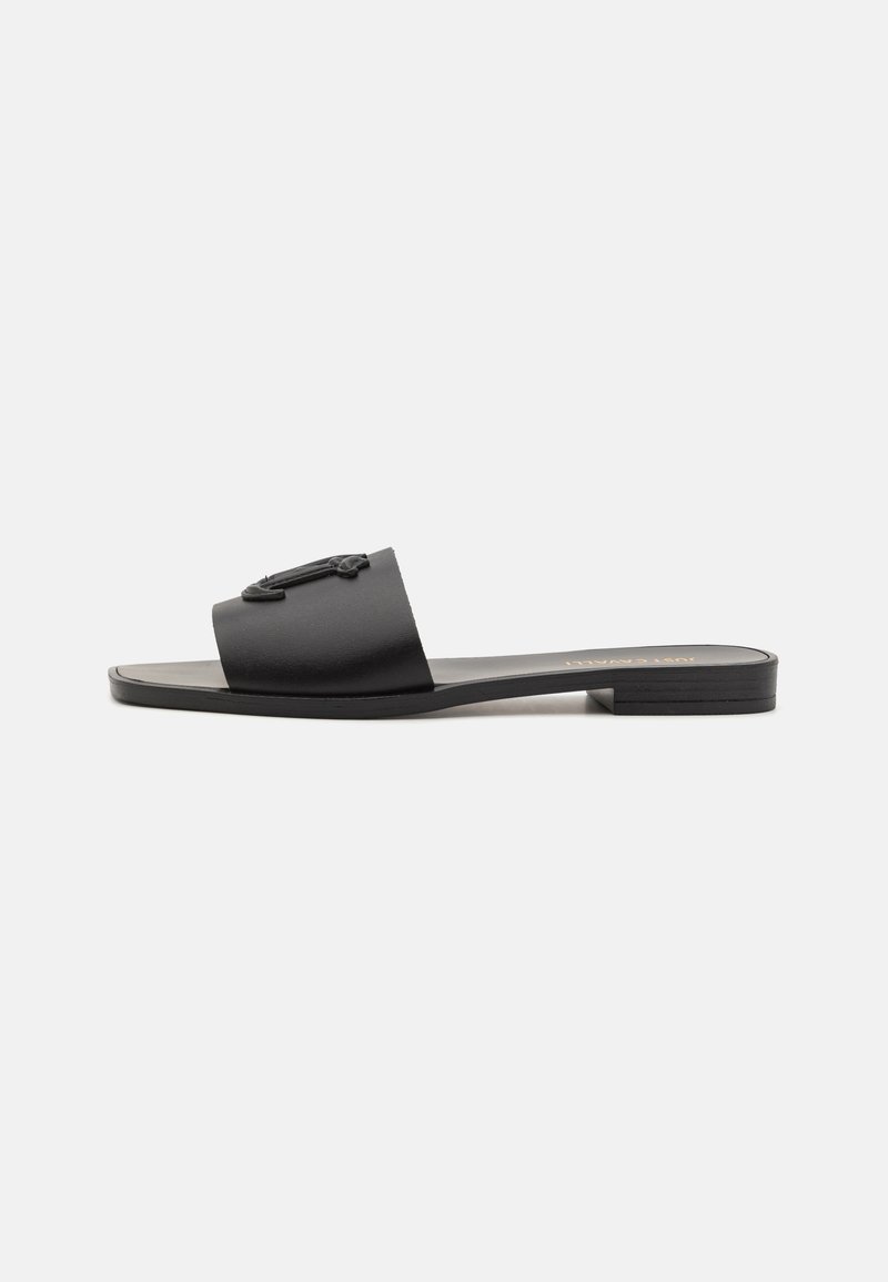 Sandale glissante noire avec une finition mate lisse, une large sangle avec un détail de logo, une semelle plate et un talon subtil. Conçue pour un port facile.