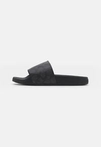Chanclas negras con una parte superior texturizada que presenta un patrón sutil, suela plana y una plantilla de goma suave, diseñadas para brindar comodidad y durabilidad.