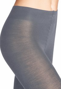 Collant grigi trasparenti con una superficie liscia, dotati di vita a coste e dettagli di cucitura discreti lungo il lato.