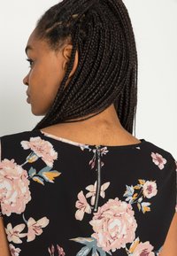 Vestido floral com flores rosa e amarelas sobre um tecido preto, com fecho zip nas costas e decote arredondado. Textura suave e leve.