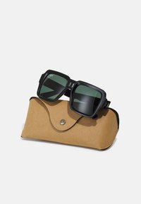 Ochelari de soare negri, cu lentile verzi, așezați pe un toc din piele bej, având un design rotund și un sistem de închidere cu capsa metalică.