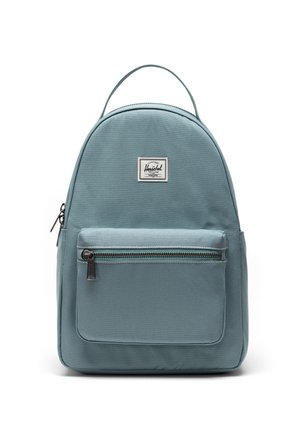 Herschel rygsæk i blødt blåt stof, rundformet med en frontlomme med lynlås og logo-patch. Har et top-håndtag til at bære.