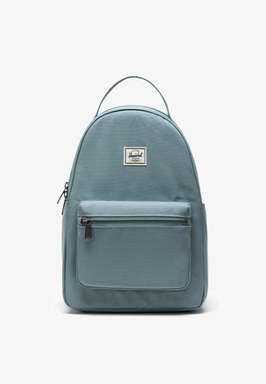 Herschel rygsæk i blødt blåt stof, rundformet med en frontlomme med lynlås og logo-patch. Har et top-håndtag til at bære.