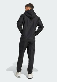 Black hooded jacket with long sleeves, paired with black cargo pants. Features include multiple pockets and a relaxed fit, suitable for casual wear.