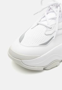 Weißer Sneaker mit Mesh-Obermaterial und Gummisohle. Verfügt über strukturierte Akzente und flache Schnürsenkel. Die Form ist an der Zehe abgerundet und mit verstärkten Nähten versehen.