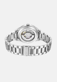 Zegarek ze stali nierdzewnej z przezroczystym tyłem, ukazującym szczegóły mechanizmu. Posiada srebrną bransoletę i zapięcie, wodoodporny do 3 ATM.