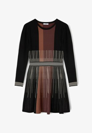 Czarna sukienka z długim rękawem, z pionowymi beżowymi i brązowymi paskami, dopasowaną talią i rozkloszowanym dołem z wzorem pasków.