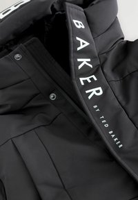 Melnas mīkstinātās jakas ar rāvējslēdzēju un spiedpogām, kas apakšējā apakšmalā ir ar tekstu "BAKER BY TED BAKER".