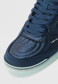 Tengerészeti kék sneaker, bőr és velúr anyagokból készült, kerek orrú, perforált részletekkel és lapos fűzőkkel. Átlátszó gumitalppal rendelkezik.