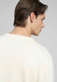 Maglione color crema realizzato in morbido tessuto a maglia, con scollo rotondo classico e vestibilità comoda, visto da dietro.