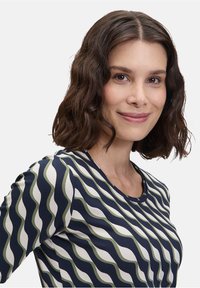 Marine-blauwe t-shirt met een golvend patroon in crème en olijfgroen. Korte mouwen, ronde halslijn en geribbelde textuur.