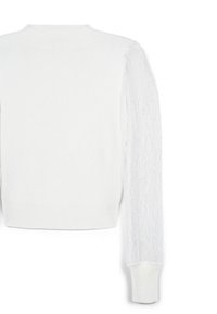Weißer Strickpullover mit hohem Hals. Ein Ärmel ist mit zarter Spitzendekoration versehen, während der andere in solidem Weiß gehalten ist. Gerippter Saum.