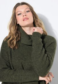 Maglione oversize in verde oliva lavorato a maglia con colletto alto e svasato e polsini a costine. Presenta un motivo testurizzato e una vestibilità rilassata.
