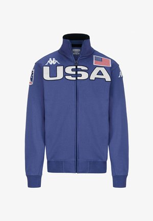 Giacca zip-up blu con grande scritta "USA" in bianco. Presenta un colletto alto, polsini a coste e un patch della bandiera americana sulla spalla.