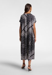 Abito nero con pattern, caratterizzato da una vestibilità ampia, maniche a cappuccio e un design lungo fino al pavimento, decorato con motivi a paisley e floreali bianchi.