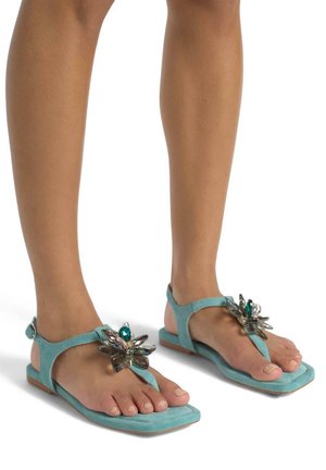 Sandalo turchese con decorazioni floreali, suola piatta e cinturino alla caviglia. Materiale morbido con una finitura testurizzata e design con punta quadrata.