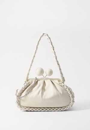 Borsa a mano in pelle crema con accenti intrecciati, pomelli di chiusura rotondi e tracolla in catena argentata rimovibile. Forma morbida e strutturata.