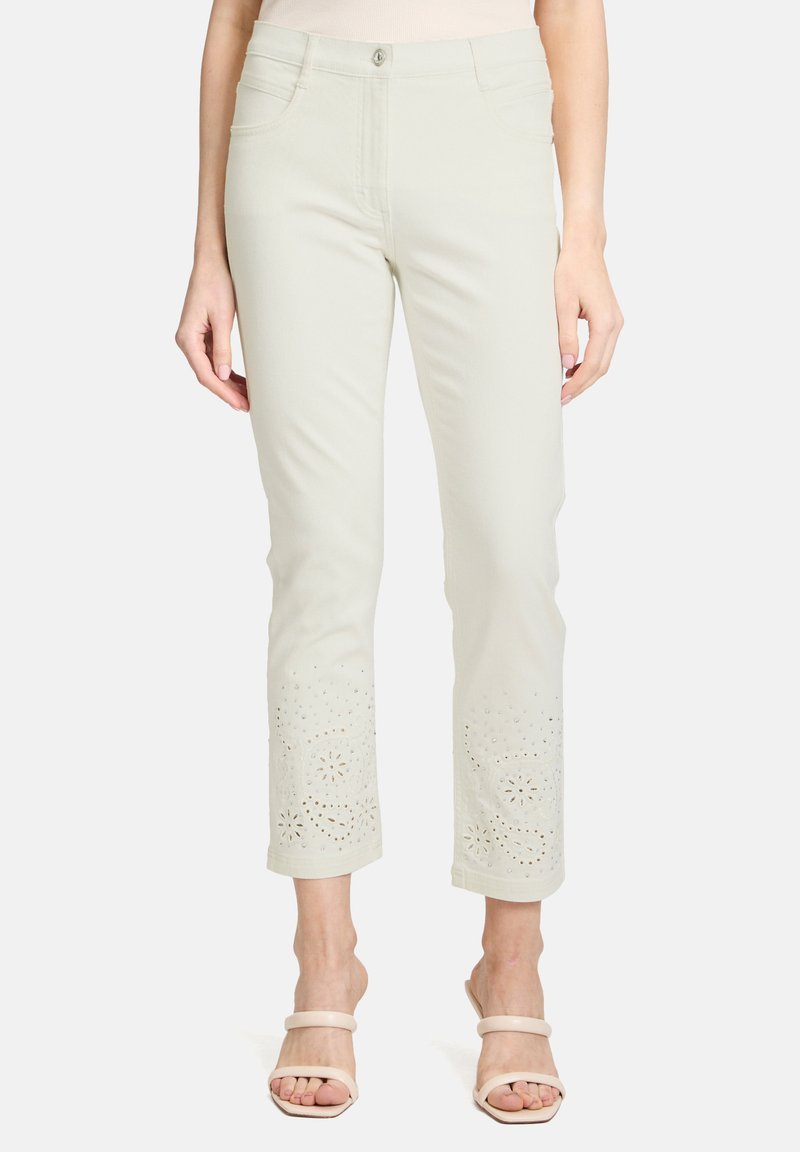 Jasno-beżowe, cropped spodnie z haftowanymi kwiatowymi wycięciami na dolnym brzegu, z klasycznym pięciokomorowym wzorem i zapięciem na guzik z przodu.