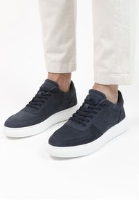 Marineblauwe suède sneakers met een witte rubberen zool, voorzien van geperforeerde details, vetersluiting en een gevoerde kraag voor extra comfort.