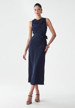 Navyblaues ärmelloses Kleid mit drapiertem Ausschnitt, Taillenschnürung und einem fließenden Rock, der bis unter das Knie reicht. Glatte Stofftextur.