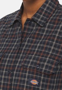 Navy- und graues kariertes Hemd aus Baumwolle, mit zwei Brusttaschen, Knopfverschluss und einem kleinen Dickies-Logo-Patch.