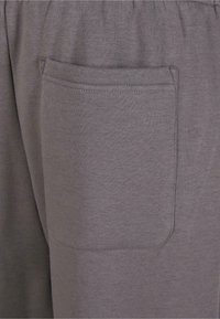 Pantalones cortos de tela gris con un bolsillo lateral, cinturilla elástica y un material suave y texturizado para mayor comodidad.