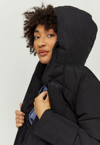 Black puffer jacket with a hood, featuring a shiny texture, zip closure, and the brand name "MAZIN" on the shoulder.