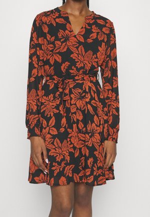 Vestito nero a maniche lunghe con motivo floreale arancione, scollo a V e cintura annodata in vita, indossato da una persona in piedi.