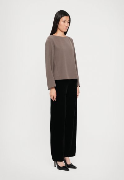 Brown long-sleeve top with a square neckline, paired with black wide-leg velvet pants and black pointed-toe heels. Smooth texture overall.