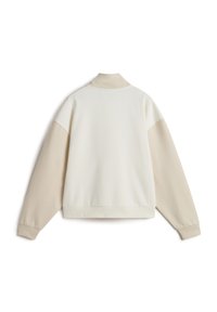 Veste pull en crème et beige, avec un col, des manches longues et un tissu texturé. Design simple avec des blocs de couleurs contrastés.