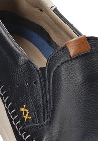 Zapato slip-on de cuero azul marino con una pestaña de acento marrón, costuras blancas y una superficie texturizada. El interior presenta un forro azul.