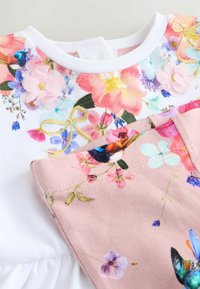 Kortærmet kjole med en blomsterprintet overdel i hvid og en lyserød nederdel med yderligere blomsterprint og broderidetaljer.