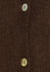 To runde hvide knapper syet på mørkebrun struktureret stof, justeret lodret med synlige sytråde.