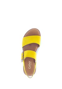 Yellow suede sandal with two wide straps, adjustable silver buckle, and brown insole. Open design, flat sole for comfort.