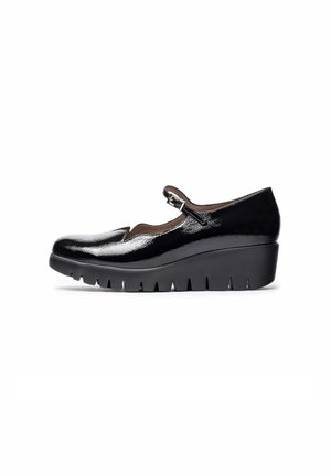 Chaussures Mary Jane en cuir verni noir avec un bout rond, un bord festonné et une boucle réglable. Semelle épaisse en wedge noir avec un motif strié.