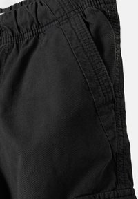 Shorts noirs avec une ceinture élastique, dotés de poches latérales et d'une texture de tissu lisse. Des coutures visibles ajoutent du détail au design.