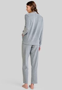 Conjunto de sudadera y pantalones gris. Tela suave, ajuste holgado, mangas largas y piernas rectas con cintura elástica. Modelo mostrado de espaldas.