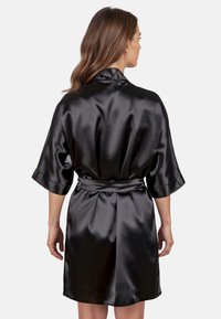 Rochie din satin negru cu cordon, cu mâneci scurte și o textură netedă. Spatele are un design plisat pentru un plus de detaliu.