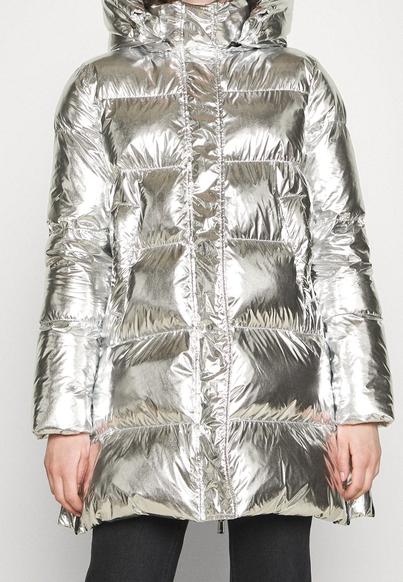 Silverfärgad pufferjacka med blänkande yta, som har huva, dragkedja fram och stora vadderade paneler. Sidofickor för ökad funktionalitet.